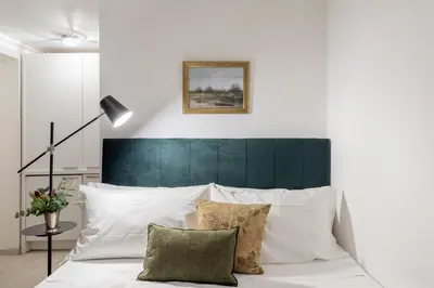 a white bed with a green headboard and pillows at GuestHost - Basic Studio - 350 m far from Fontana di Trevi in Rome
