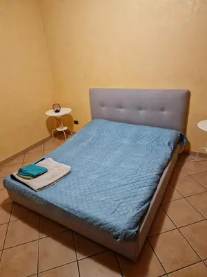 a bed with a blue comforter and a table at A 2 passi dal cuore di Roma in Rome