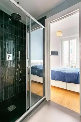 a bathroom with a glass shower and a bed at La finestra verde in Rome