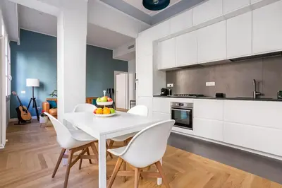 a white kitchen with a white table and chairs at La finestra verde in Rome
