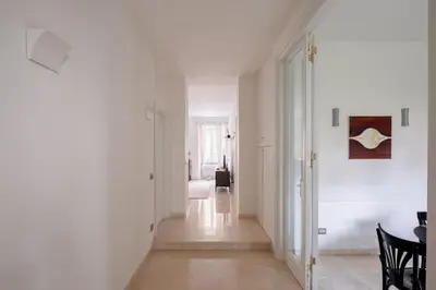 a hallway with white walls and a table and chairs at Nostromondo Basilica Apartment in Rome