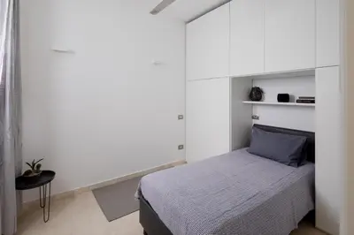 a bedroom with a bed and a white wall at Nostromondo Basilica Apartment in Rome