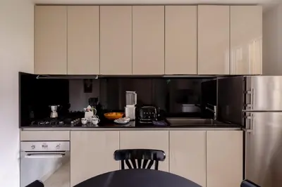 a kitchen with white cabinets and a stainless steel refrigerator at Nostromondo Basilica Apartment in Rome