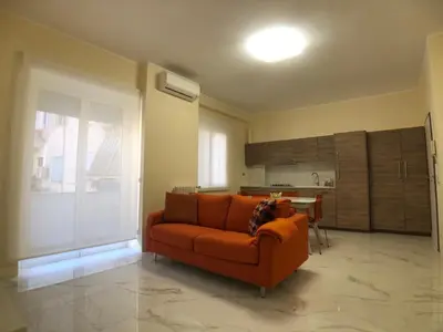 a living room with an orange couch and a kitchen at Maison Carlotta In Vatican in Rome