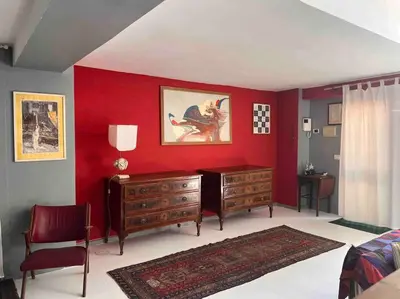a bedroom with a red wall with a dresser and a desk at trastevere' s Musa in Rome