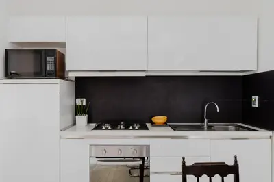 a kitchen with white cabinets and a sink and a microwave at Minerva's Place in Rome