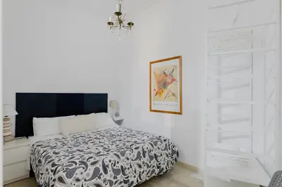 a white bedroom with a bed and a chandelier at Minerva's Place in Rome