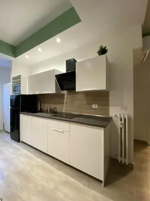 a kitchen with white cabinets and a black refrigerator at La Casa di Marco Polo in Rome