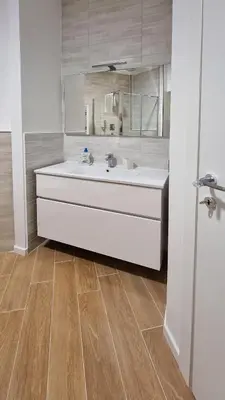 a bathroom with a white sink and a wooden floor at Vignola New Apartment in Rome