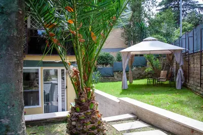 a palm tree in a yard with an umbrella at Garden City House Roma - Casa con giardino privato in Rome