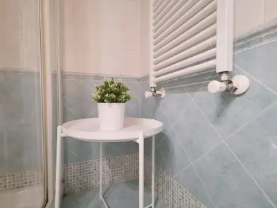 a small white table with a plant on it in a bathroom at La Dimora Dante in Rome