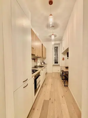 a kitchen with white cabinets and a wooden floor at Ovidio Luxury in Rome