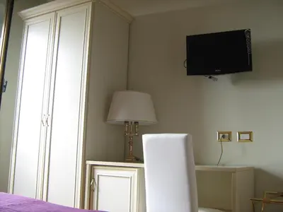 a bedroom with a tv on the wall and a lamp at Appia Nuova Holiday B&B in Rome