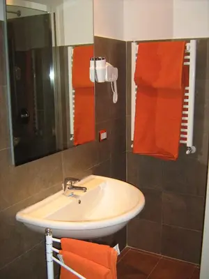 a bathroom with a sink and a mirror and orange towels at Appia Nuova Holiday B&B in Rome