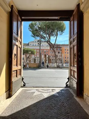 an open door to a building with a tree in the background at Torre Argentina Apartment in Rome
