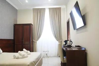 a hotel room with two beds and a desk and a television at Monti 66 Hotel in Rome