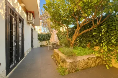 a courtyard with a tree and a table with an umbrella at 15 MIN FROM THE VATICAN Wi-fi and garden in Rome
