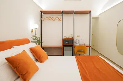 a bedroom with a white bed with orange pillows at Charm&Bella GuestHouse in Rome