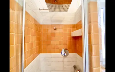 a bathroom with a shower with orange tile at Charming mini apartment near Vatican with parking in Rome