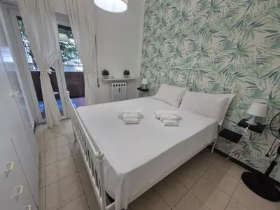 a white bed in a bedroom with a green and white wallpaper at Inn Trastevere in Rome