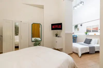 a white bedroom with a bed and a mirror at Rhome_Hub in Rome