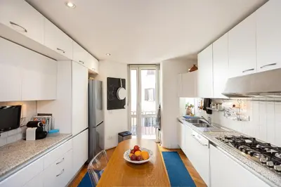 a kitchen with white cabinets and a bowl of fruit on a wooden table at San Gioacchino View by Rental in Rome in Rome