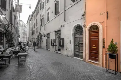a street with people sitting at tables in an alley at Daplace - Arianna Apartment in Rome
