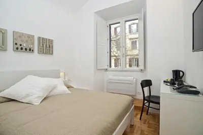 a bedroom with a bed and a desk and a window at Vatican Charme in Rome
