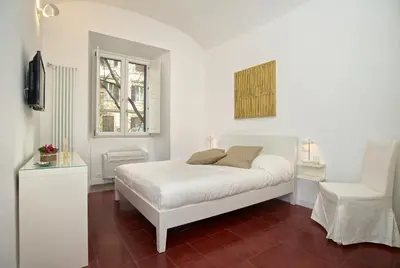 a white bedroom with a white bed and a window at Vatican Charme in Rome