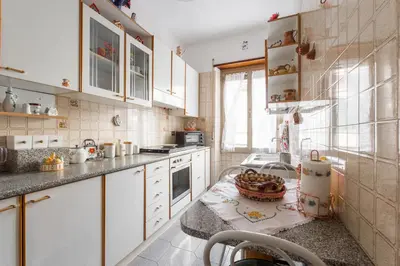 a kitchen with white cabinets and a table with a bowl on it at family home in Rome