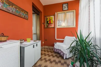 a living room with orange walls and a chair and a plant at family home in Rome