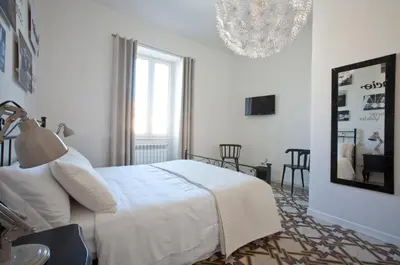 a white bedroom with a bed and a chandelier at Saint Peter's Keys in Rome