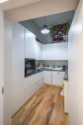 a kitchen with white cabinets and a hardwood floor at Navona Charming Balcony in Rome