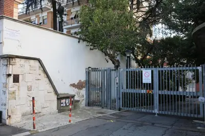 a blue gate in front of a building with a tree at Casa Piccole Ancelle di Cristo Re in Rome