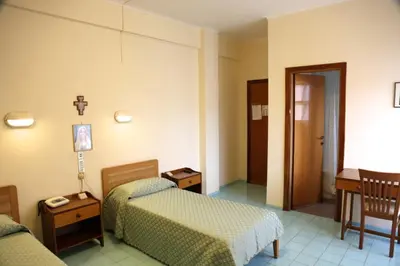a hotel room with two beds and a chair at Casa Piccole Ancelle di Cristo Re in Rome