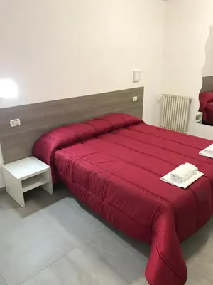 a bedroom with a red bed with a red blanket at Tiburtina Royal Suites in Rome