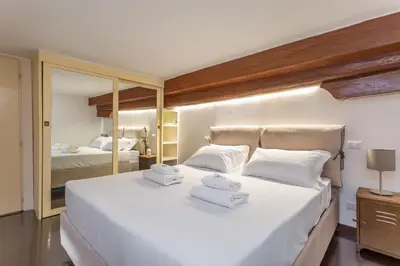 a bedroom with a large white bed with mirrors at Trastevere San Calisto 3 BDR Apartment in Rome
