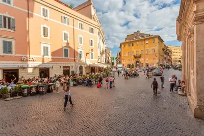a crowd of people walking down a street with buildings at Trastevere San Calisto 3 BDR Apartment in Rome