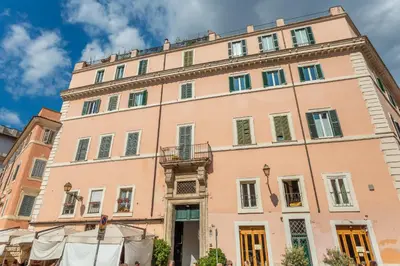 a large pink building with a balcony at Trastevere San Calisto 3 BDR Apartment in Rome