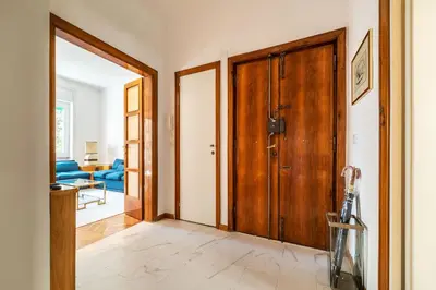 a hallway with a wooden door and a living room at GuestHost - Sapienza & Villa Borghese Comfy Apartment in Rome