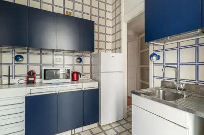 a kitchen with blue cabinets and a white refrigerator at GuestHost - Sapienza & Villa Borghese Comfy Apartment in Rome