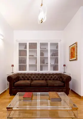 a living room with a brown couch and a glass table at Ripetta Beauty House in Rome