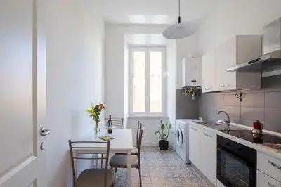 a white kitchen with a table and a dining room at Lunaria Apartment Vatican Rome in Rome