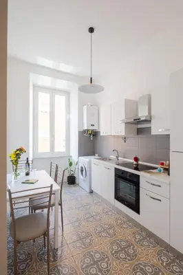 a white kitchen with a table and a table and chairs at Lunaria Apartment Vatican Rome in Rome