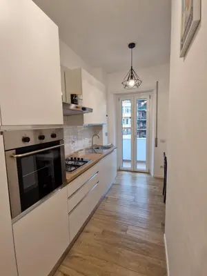 a kitchen with white cabinets and a wooden floor at La casa di Eurialo in Rome