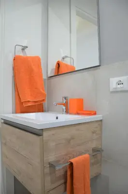 a bathroom with a sink and a mirror and orange towels at Casa Pesa 2 rooms 2 baths Rome center in Rome