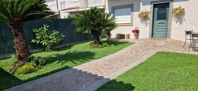 a garden with palm trees and a house with a door at Castelbarco House A in Rome