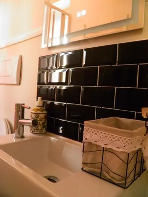 a sink in a bathroom with a black tiled wall at Auditorium Deluxe in Rome