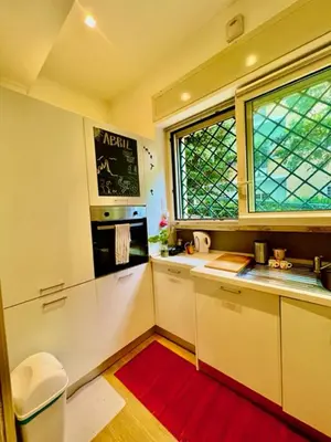 a kitchen with white cabinets and a red rug at Auditorium luxury suite Roma in Rome