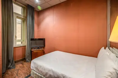 a small bedroom with a bed and a television at Castro Pretorio 64 Easy Rooms in Rome